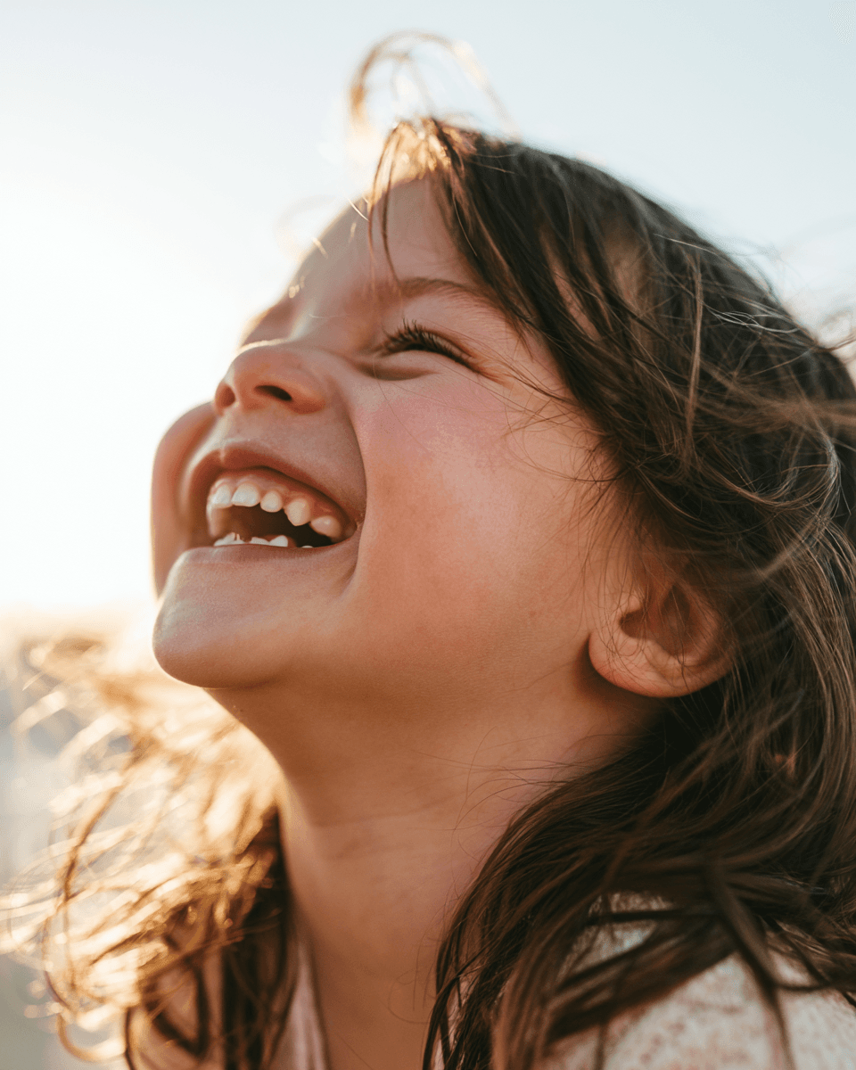Un enfant qui rit, le visage tourné vers le soleil